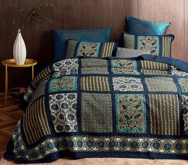 Un lit décoré de coussins et de couvertures enveloppés dans des bojagi.
